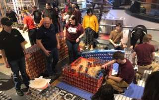 People constructing something out of cans during Build Night for canstruction