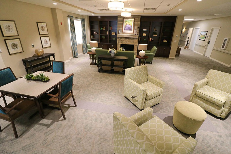 Eastbrook Nursing Home recreation area with tables, chairs, comfortable chairs, couches, fireplace, and bookshelves